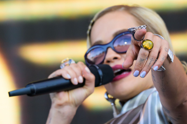 Rita Ora singing into a microphone and pointing